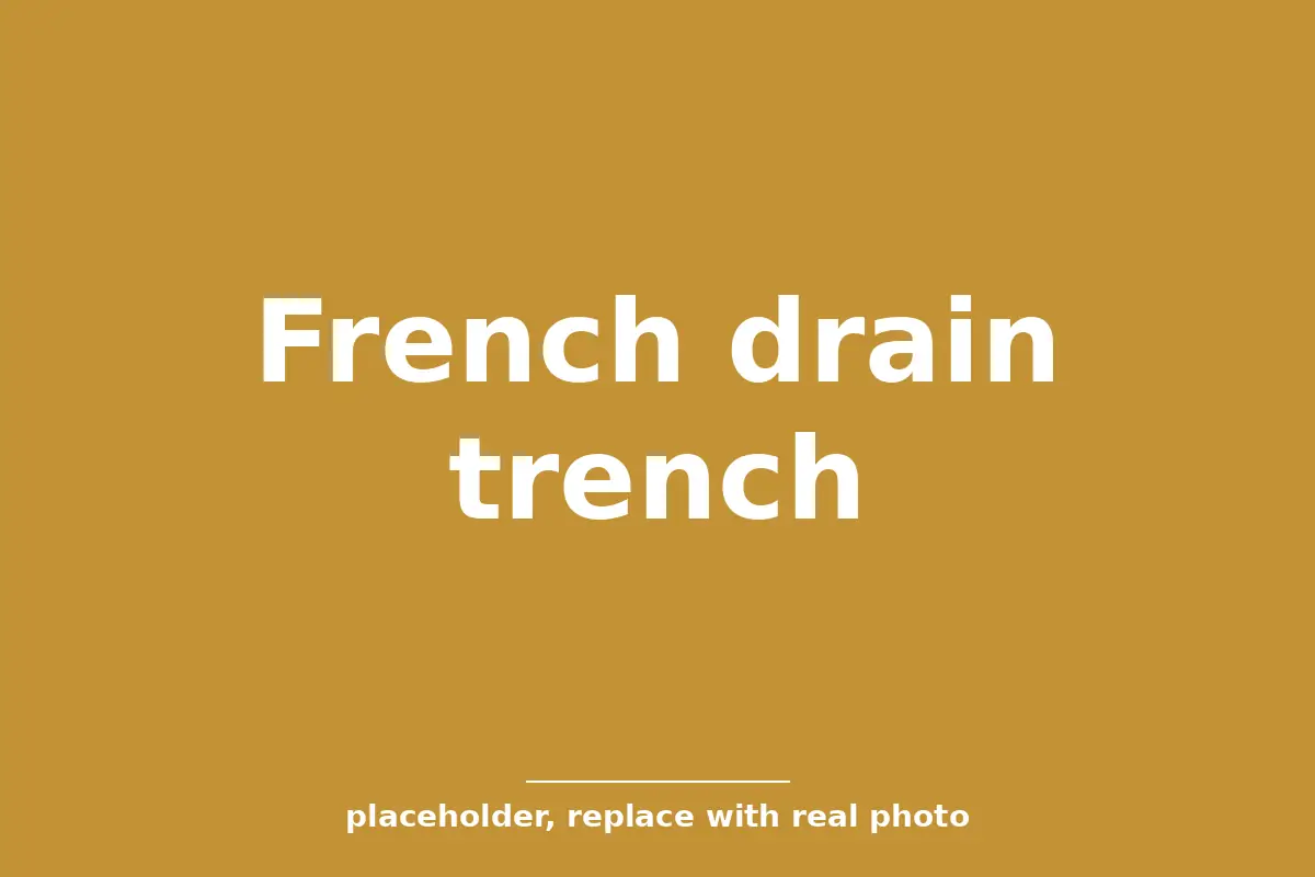 French drain trench with gravel and perforated pipe beside a Tulsa home foundation for drainage